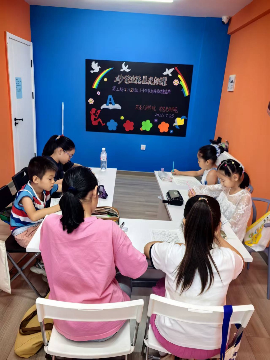 孩子们在真实课堂中围桌完成写作练习,画面以背影和侧面为主
