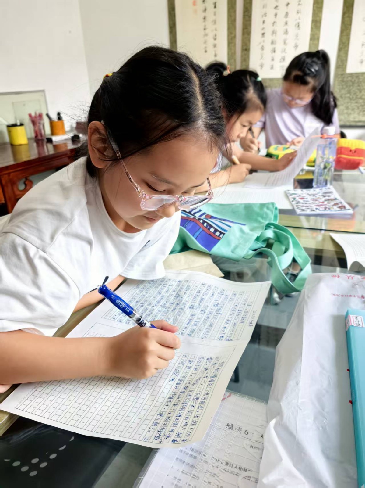 孩子们在课堂上低头认真完成作文练笔,前景学生正在书写,后方同学也在写作